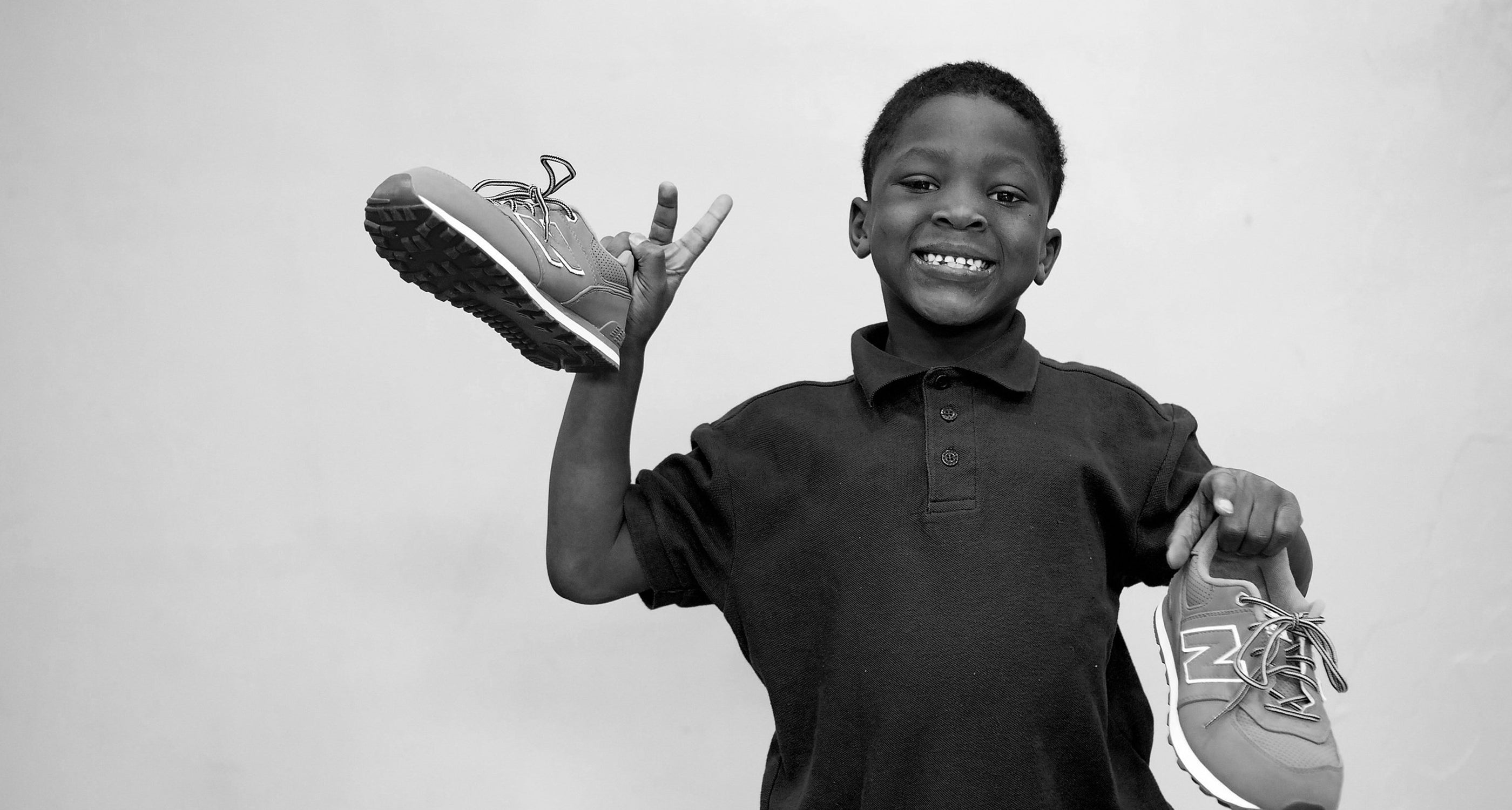 Child holding up New Balance Sneakers